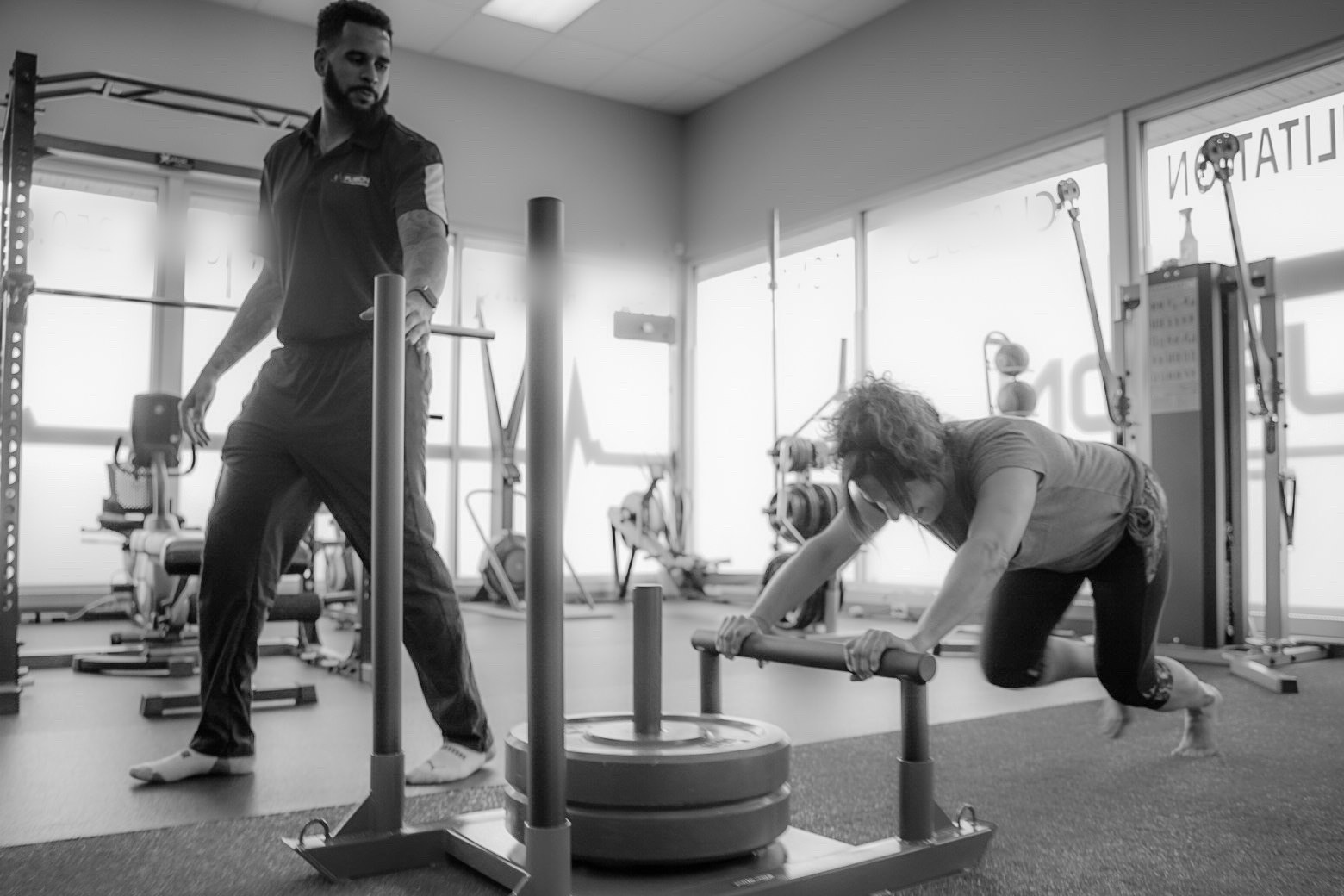 Cassidy watches a client push a weighted sled across the studio floor